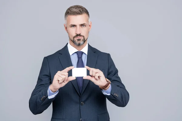 Mature man banker with grizzled hair in suit showing credit or debit card copy space, manager — Stock Photo, Image