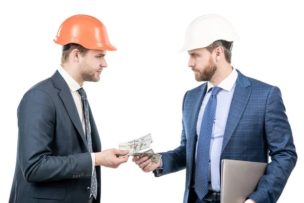 Investidores homens de terno e capacete de segurança dando ou tomando dinheiro e segurar computador, investimento — Fotografia de Stock