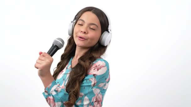 Il cantante bambino allegro ascolta la musica in cuffie e canta la canzone in microfono, scuola vocale — Video Stock