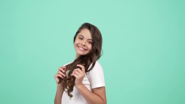 Teen dívka dotknout její dlouhé kudrnaté vlasy se šťastnou tváří a foukání polibek, krása — Stock video