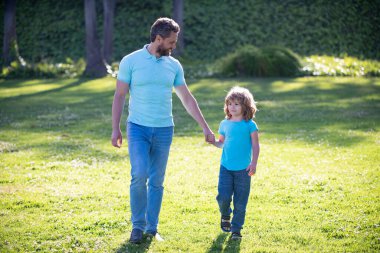 Çocukluk ve ebeveynlik. Çimlerin üzerinde küçük bir çocuğu olan ebeveyn. Baba ve çocuk yazın