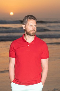 Gündoğumu plajındaki beyaz adam. Gömlekli sakallı adam. Yaz modası. yaz tatili