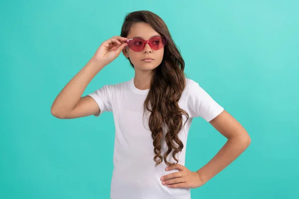 Sério adolescente menina longo cabelo encaracolado em óculos de sol estilo casual no fundo azul, estilo de verão — Fotografia de Stock