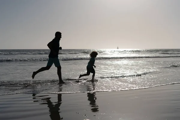 Ojciec i syn sylwetki działa zabawy i poczuć wolność na plaży letniej, rodzina — Zdjęcie stockowe