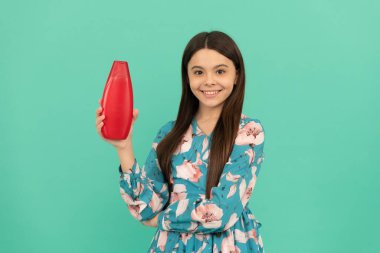 Uzun saçlı gülümseyen çocuk şampuan şişesi, kuaför.