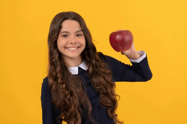 Feliz adolescente chica mostrando rojo vitamina manzana para el almuerzo sobre fondo amarillo, vitamina —  Fotos de Stock