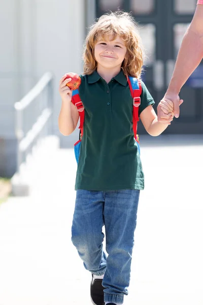 Glad skolpojke barn hålla äpple och fäder hand kommer tillbaka från skolan, skolkamrat — Stockfoto