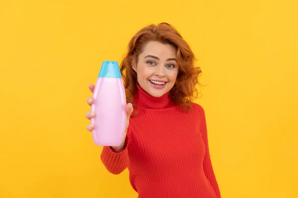 Roodharige dame presenteert cosmetisch product. gelukkige vrouw gebruik douchegel. vrolijk meisje krullend haar — Stockfoto