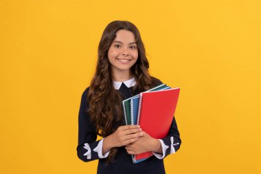 gülümseyen çocuk okul defterlerini tut ev ödevleri için sarı arka plan ve eğitim üzerine çalış