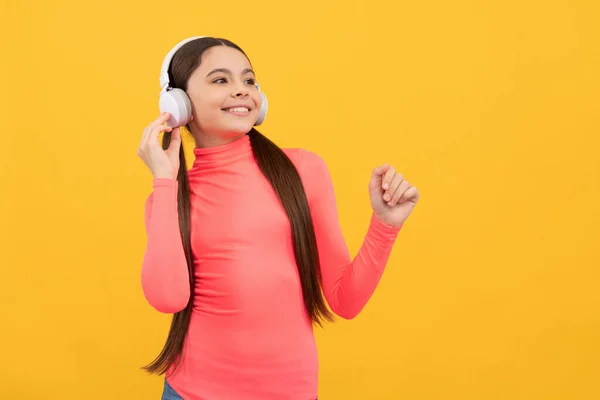 Heureux adolescent fille écouter de la musique dans les écouteurs sur fond jaune, espace de copie, appareil numérique — Photo