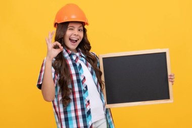 winking kid in helmet presenting school blackboard with advertisement show ok, copy space, approval