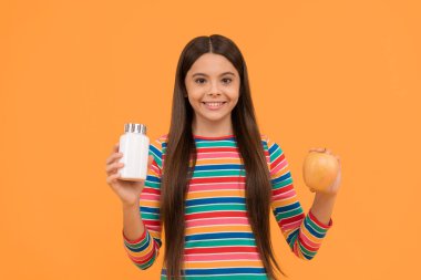 Güçlü ol ve vitamin al. Mutlu çocuk elma ve takviye şişesi tutuyor. Elma takviyesi