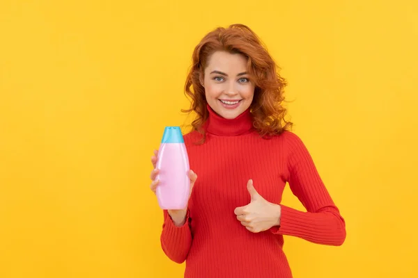 Donna felice utilizzare gel doccia. ragazza capelli ricci tenere shampoo bottiglia spettacolo pollice in su. — Foto Stock