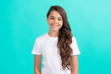 Mavi arka planda beyaz gömlekli, uzun kıvırcık saçlı mutlu çocuk.