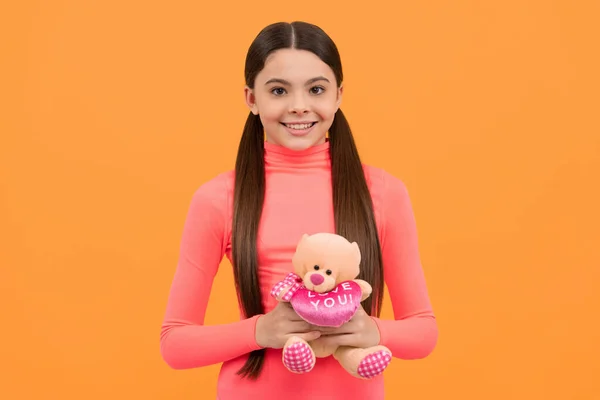 Menina adolescente feliz com brinquedo de ursinho de pelúcia para dia dos namorados no fundo amarelo, amor — Fotografia de Stock