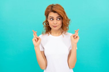 Kıvırcık saçlı hayalperest kız mavi arka planda dilek tutuyor, hayal kuruyor.