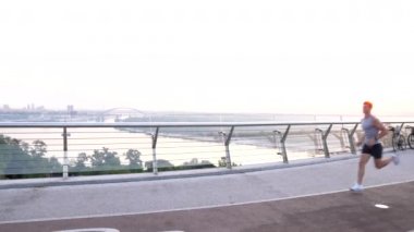 Spor kıyafetli atletik kaslı adam sabahları camsı köprüde koşuyor, anaerobik.