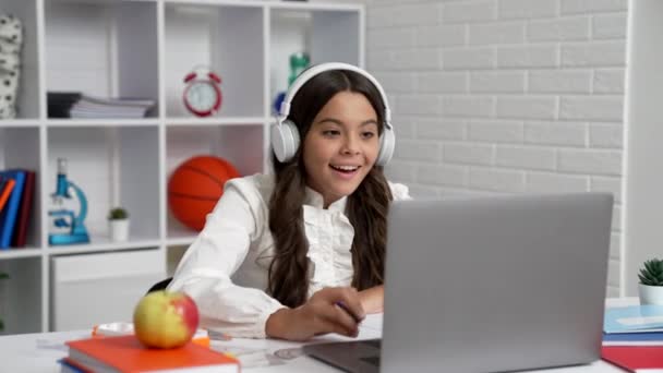 Весела дитина в шкільній формі і навушники закінчили онлайн-урок на ноутбуці, вебінар — стокове відео