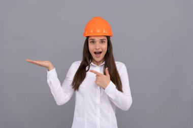 Koruyucu miğferli, tişörtlü, parmakla işaret eden ve fotokopi alanı ve reklam sunan hayret verici kadın..