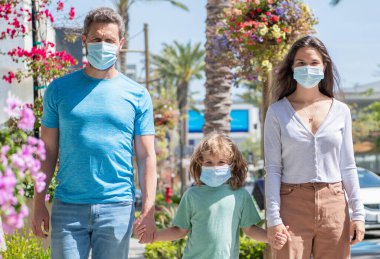 Anne ve babanın genç ailesi koruyucu bir maske takıyor.