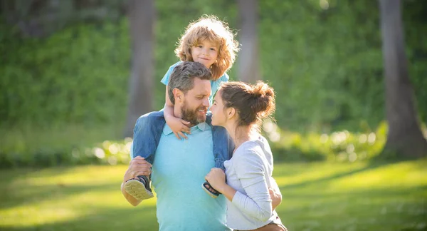 Familia feliz de la madre y el padre llevando niño niño en hombros verano al aire libre, disfrute — Foto de Stock