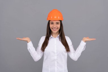 Koruyucu kasklı ve beyaz gömlekli mutlu kadın ürün, fotokopi alanı, reklam sunar.