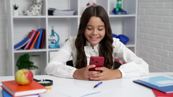 Feliz estudiante en uniforme escolar escribiendo y leyendo mensajes de texto en el teléfono inteligente, mensajería — Vídeos de Stock