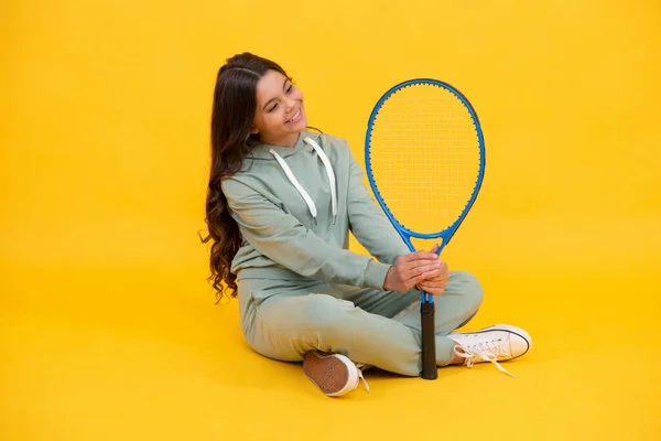 Glad tonåring flicka i sportkläder hålla tennisracket på gul bakgrund, sport — Stockfoto