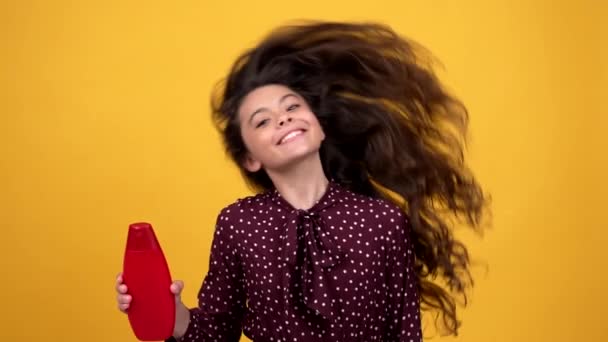 Feliz belleza niño ondeando su hermoso cabello ondulado saludable que ofrece cosméticos champú, belleza adolescente. — Vídeos de Stock