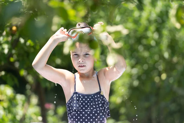 Cieszymy się letnim dniem. Mokre dziecko zdejmuje gogle. Dziewczyna opala się na podwórku. Wakacje — Zdjęcie stockowe