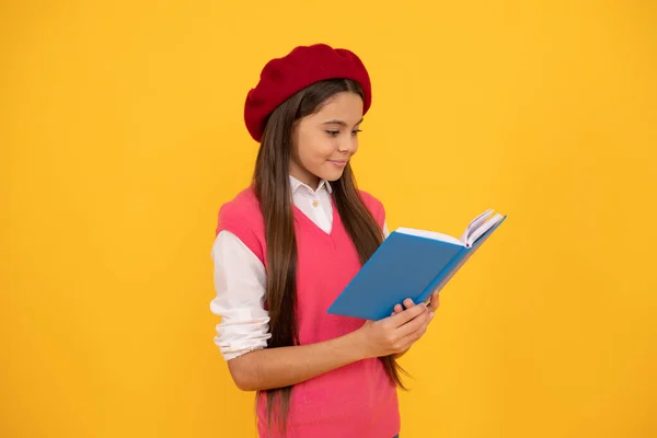Счастливая школьница-подросток в книжке для чтения на желтом фоне, чтение — стоковое фото