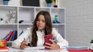 serious kid using smartphone for online education at home, video chat