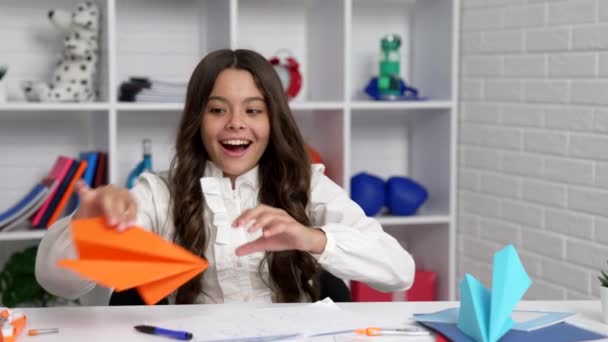 Cheerful child writing homework in workbook and playing paper plane celebrating success, fun — Video