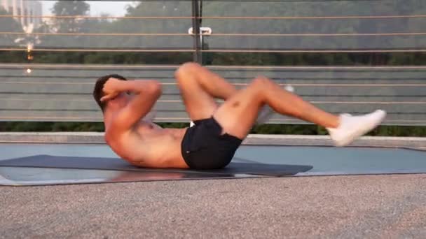 Sportman werken aan zijn buikspieren op fitness mat outdoor, fit lichaam — Stockvideo