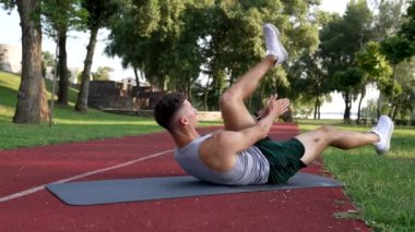 sportsman crunch with clapping on fitness mat outdoor, sport training