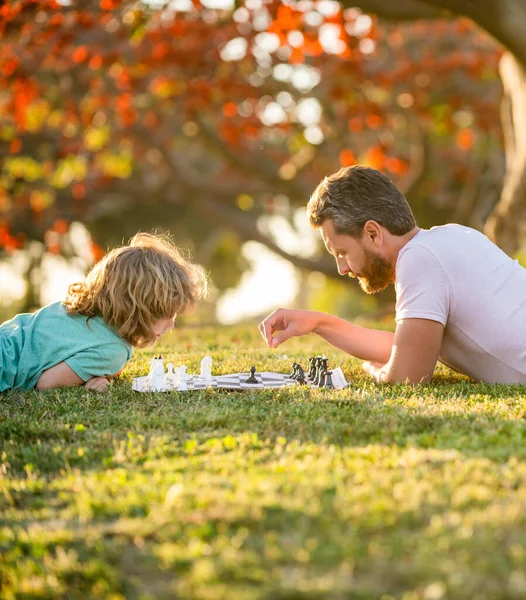 Pai e filho jogando xadrez na grama verde. Dia dos pais. família feliz. parentalidade — Fotografia de Stock