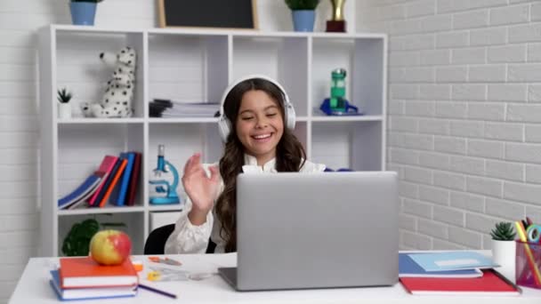 Fröhliche Schülerin mit Kopfhörern hört Musik und hat Spaß nach Webinar am Laptop, Kindheit. — Stockvideo