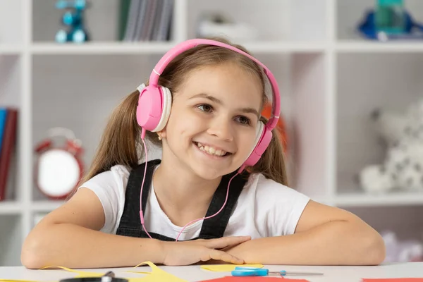Χαρούμενο παιδί ακούει μουσική στα ακουστικά στο μάθημα του σχολείου στην τάξη, online εκπαίδευση — Φωτογραφία Αρχείου