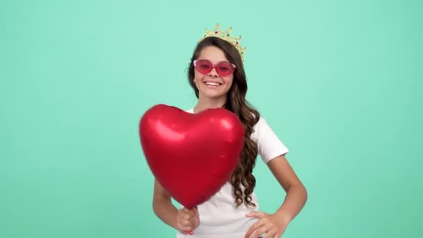 Enfant heureux dans des lunettes de soleil et couronne de princesse avec ballon de fête de coeur montrer geste de paix, reine du bal — Video