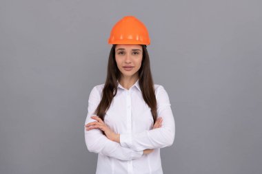 Koruyucu kasklı ve beyaz gömlekli kendine güvenen bir kadın el ele tutuşup iş yapıyor.