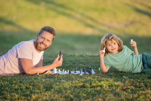Heureux famille de père homme et fils enfant jouer aux échecs sur herbe verte dans le parc en plein air, amitié — Photo