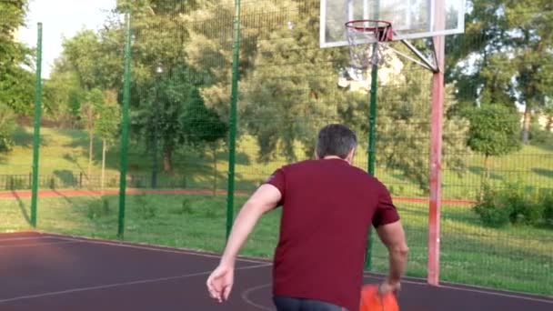 Vue arrière de l'homme jouant au basket jeter le ballon dans le panier, activité estivale — Video