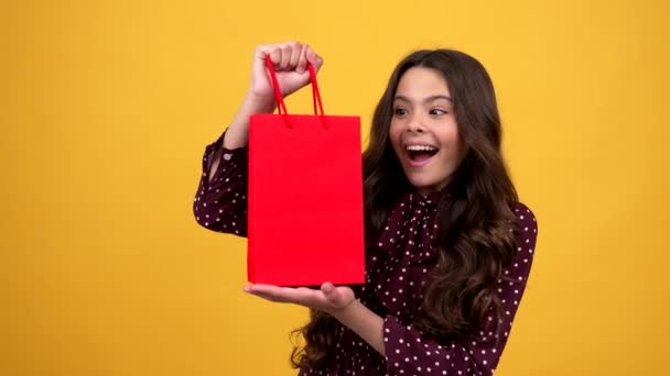 Χαρούμενο παιδί αισθάνεται έκπληξη μετά από σκέψη τι είναι μέσα στην τσάντα αγορών, ψώνια — Αρχείο Βίντεο