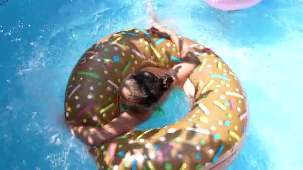 Menina nadar na piscina de donut flutuar na piscina exterior no dia ensolarado de verão, flutuação — Vídeo de Stock