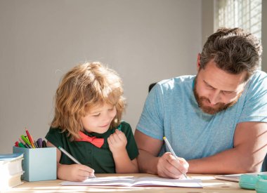 Ebeveynlik. Evde konsantre baba ve oğul yazıları. Aile günü. Çocuk öğretmenle ders çalışıyor.