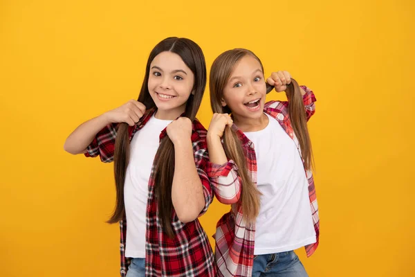 Niños felices con camisa a cuadros casual sostienen el pelo largo y recto sobre fondo amarillo, cabello —  Fotos de Stock