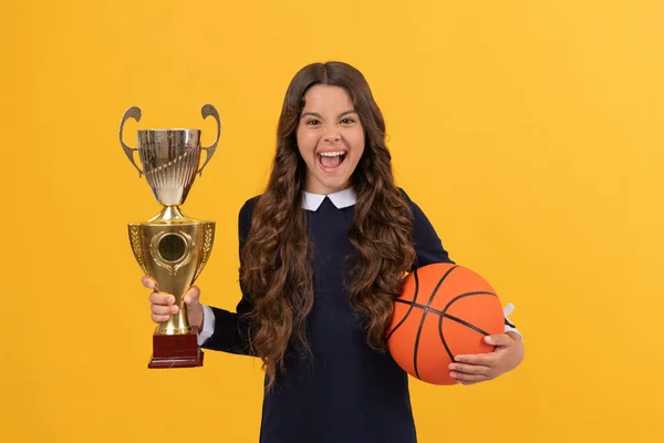 Menina adolescente feliz segurar bola de basquete e copo campeão no fundo amarelo, felicidade — Fotografia de Stock