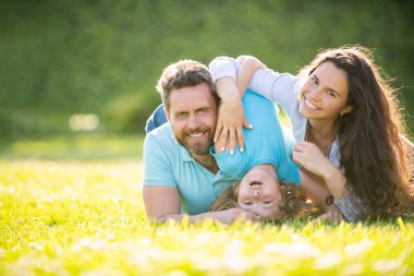 Anne, baba ve oğulun mutlu ailesi yaz parkında yeşil çimlerde, ailede rahatlayın.