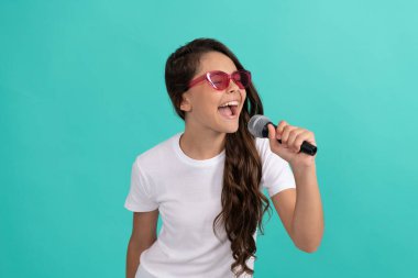 Karaoke 'de iyi eğlenceler. Karaoke çocuk şarkıcısı mavi arka plan. Mutlu çocuk mikrofona şarkı söylüyor. müzik.