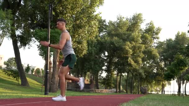 Musculoso hombre calentando con espalda embestida ejercicio al aire libre, entrenamiento — Vídeos de Stock